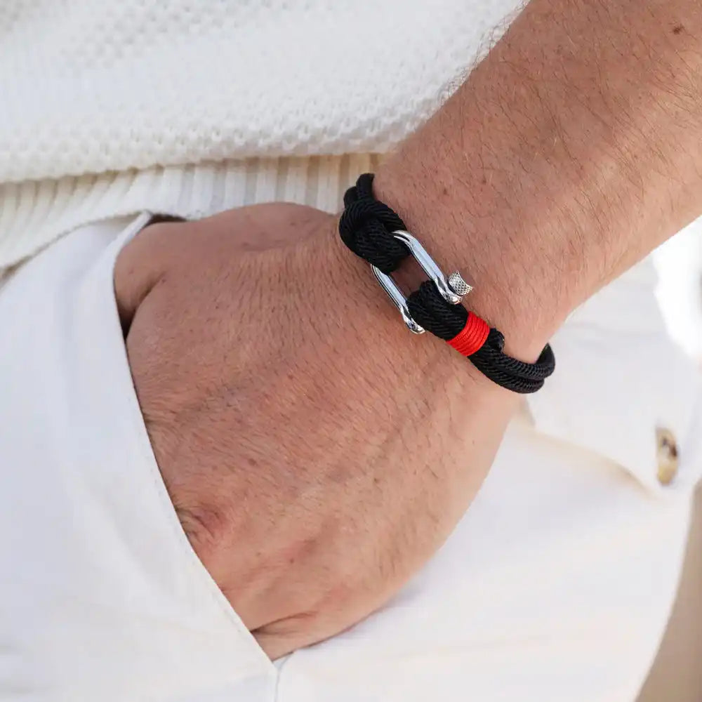 Bracelet en corde noire avec un fermoir à boucle en argent et une bande accent rouge.