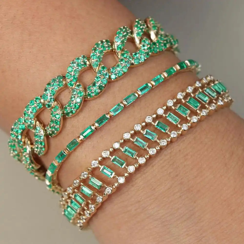 Un tas de trois bracelets étincelants en émeraude verte et en diamant sur un poignet.